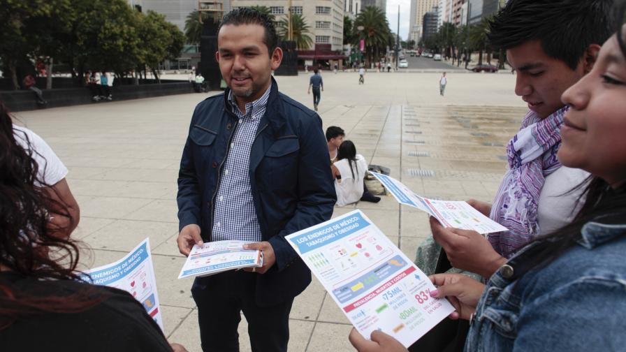 A man hands out leaflets to a small group of people on the street